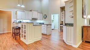 A spacious kitchen with white cabinetry, a central island with stools, and a clock on the wall. - 4 Mi to WEC & 10 Mi to Hits, Golf Course Home (Ocala)