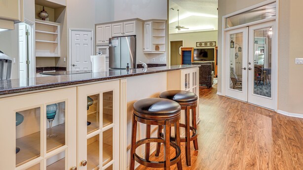 A modern kitchen with white cabinetry, a stainless steel refrigerator, and a wooden countertop. There are two bar stools and a glass backsplash. - 4 Mi to WEC & 10 Mi to Hits, Golf Course Home (Ocala)