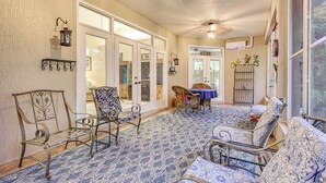 A sunlit room with a patterned carpet, metal chairs, a wicker table, and a glass door leading to another room. - 4 Mi to WEC & 10 Mi to Hits, Golf Course Home (Ocala)
