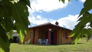 A small house with a tiled roof, a porch with chairs, and a grassy yard. - Chalosse - Mugron - Gîte (MUGRON)