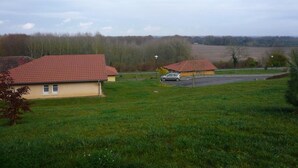 A rural setting with two houses, a car, and a field. - Chalosse - Mugron - Gîte (MUGRON)