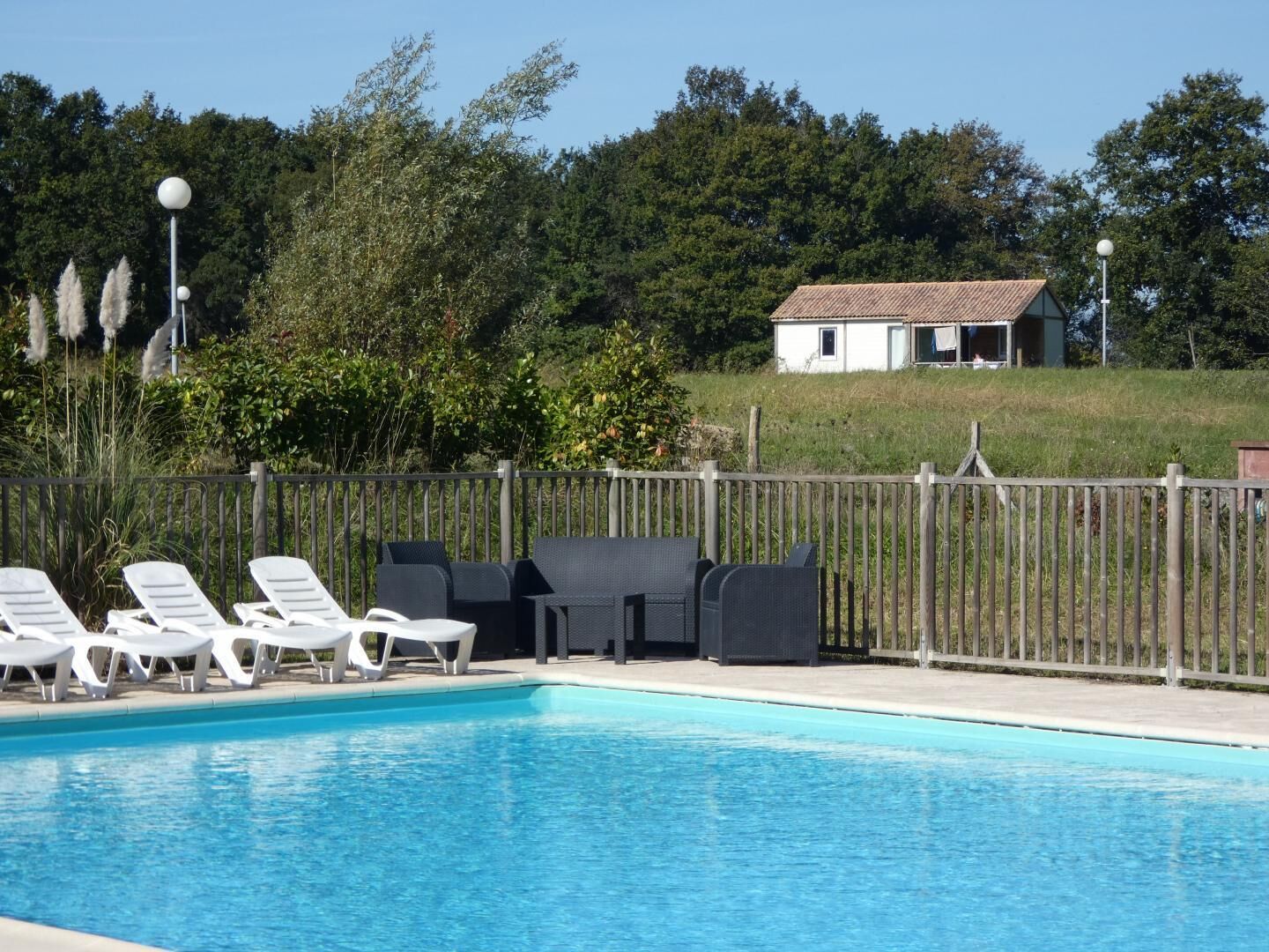 Ein Schwimmbecken mit Liegestühlen und einem umzäunten Bereich.