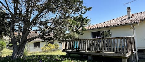 A house with a balcony, surrounded by a garden with various flowers.
