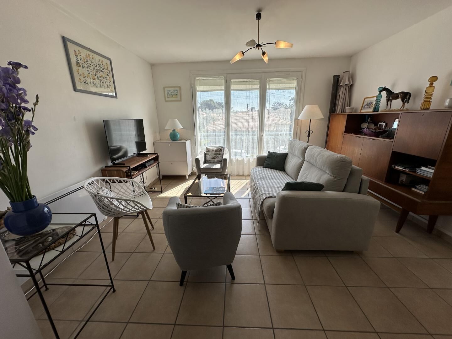 Un salon comprenant un canapé, un fauteuil, un téléviseur et une table à manger.