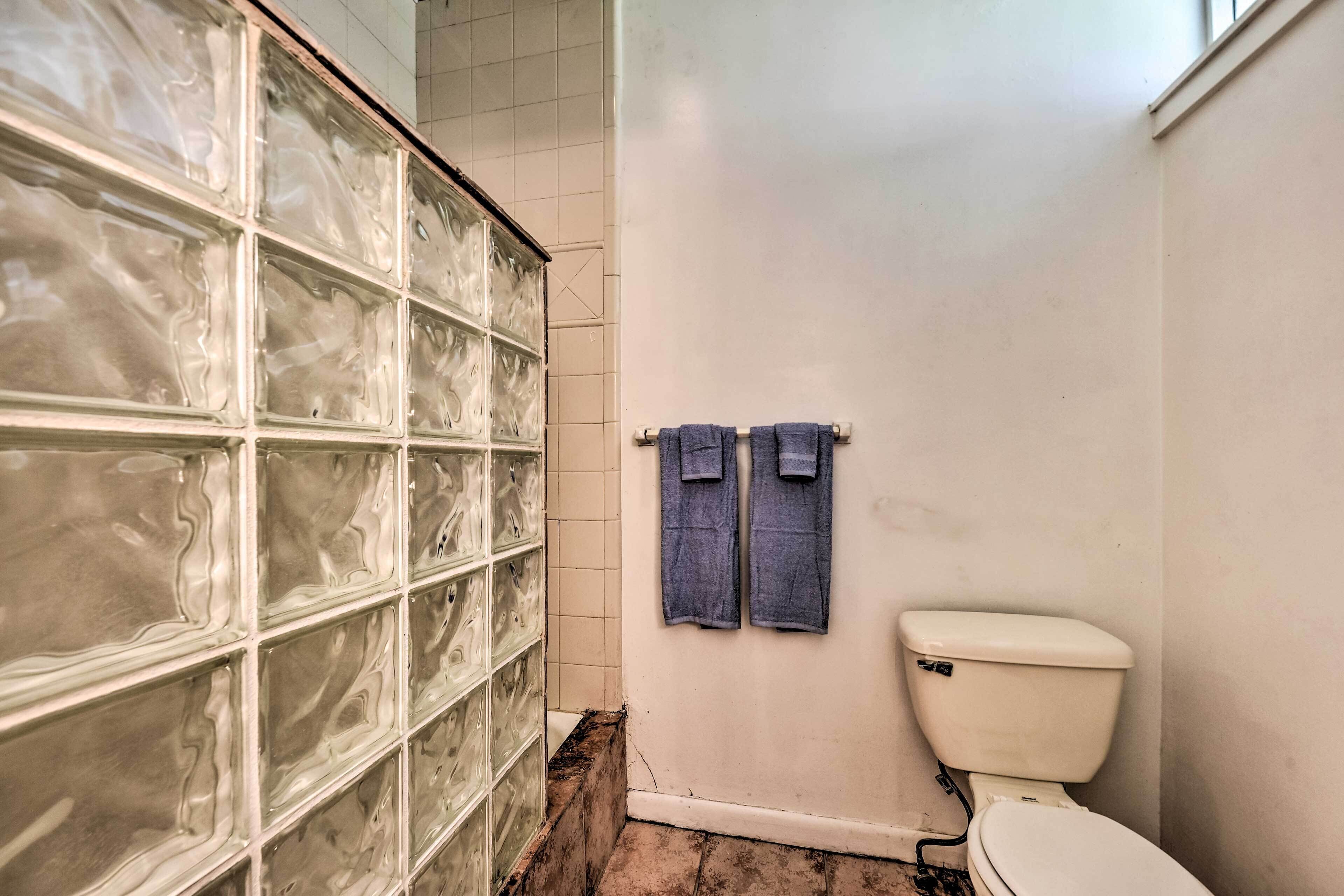 Une salle de bain avec un mur carrelé, des toilettes et un porte-serviettes avec deux serviettes.