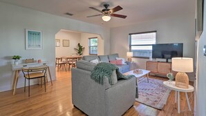 A living room with a grey sofa, a dining table, chairs, a TV, and a ceiling fan. - < 9 Mi to Downtown Miami - Modern Getaway (Miami Springs)