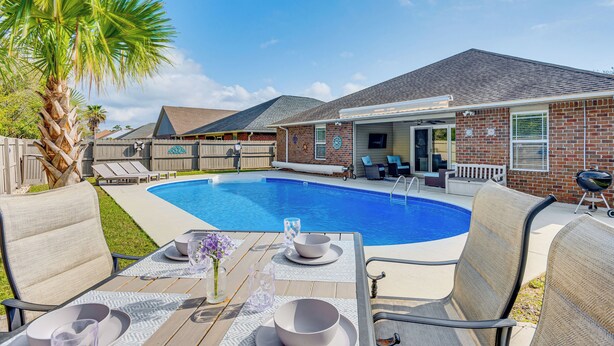 A backyard with a swimming pool, outdoor seating, and a barbecue area. - Comfortable Pensacola Home w/ Private Pool! (Pensacola)