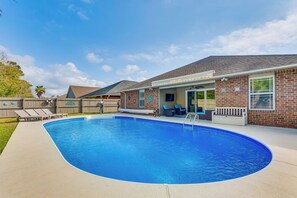 Ein Garten mit Swimmingpool, überdachter Terrasse und einem Ziegelhaus.