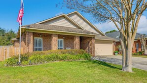A residential house with a brick facade, a garage, and a well-maintained lawn. - Comfortable Pensacola Home w/ Private Pool! (Pensacola)