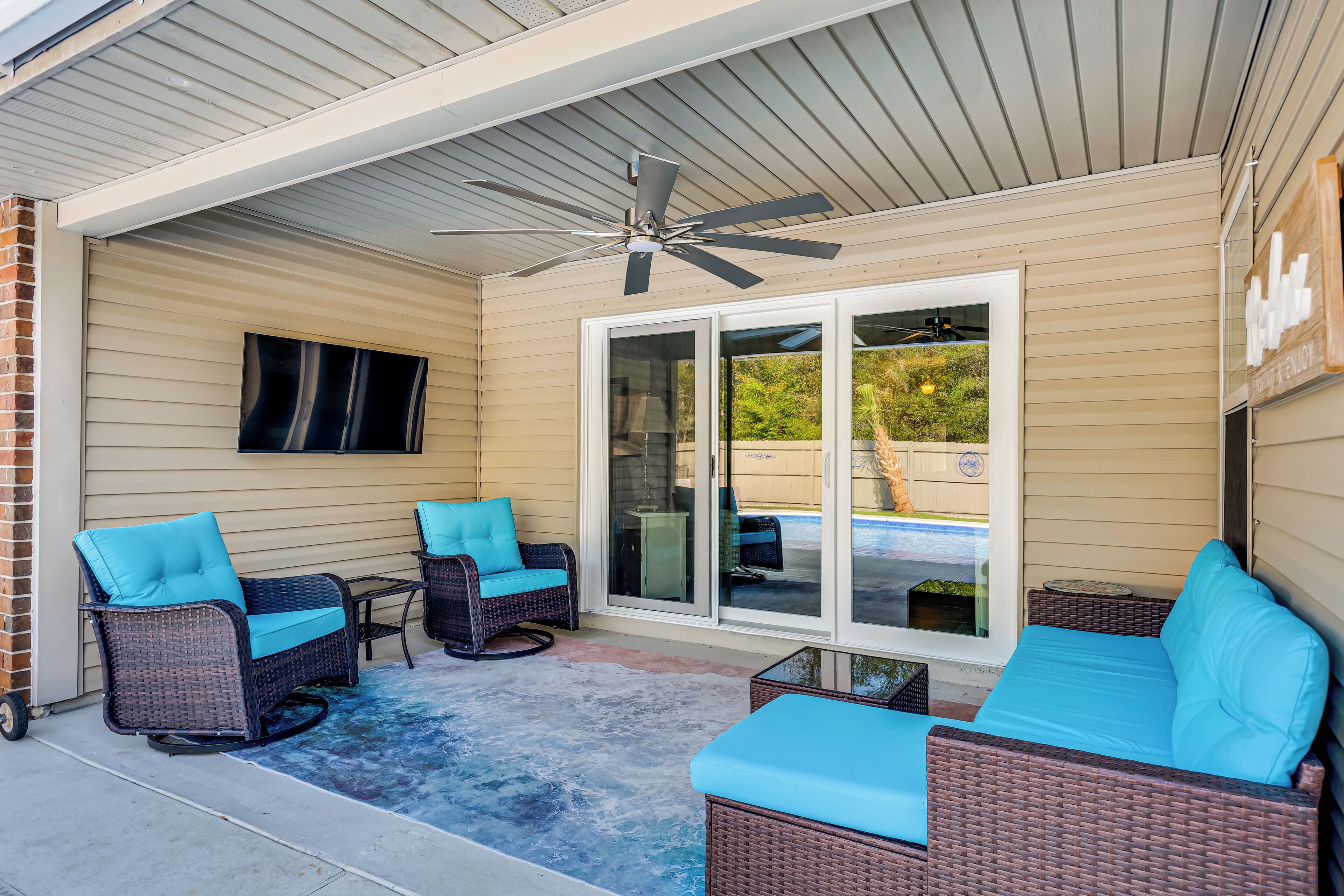 A covered patio with wicker furniture, a ceiling fan, and a sliding glass door.