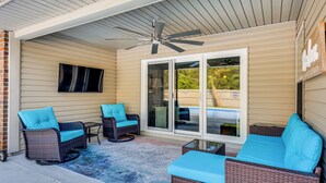 A covered patio with wicker furniture, a ceiling fan, and a sliding glass door. - Comfortable Pensacola Home w/ Private Pool! (Pensacola)