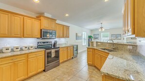A kitchen with wooden cabinets, granite countertops, stainless steel appliances, and a ceiling fan. - Comfortable Pensacola Home w/ Private Pool! (Pensacola)