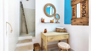 Ein Badezimmer mit einem Holzkosmetikschrank, einem runden Spiegel und einem Ablagefach für Pflegeprodukte.