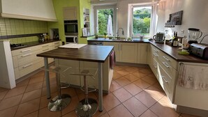 Une cuisine moderne avec un îlot central, des armoires blanches et un mur d’accent vert.