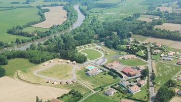 Eine Luftaufnahme einer ländlichen Gegend mit einem sich schlängelnden Fluss, grünen Feldern und verstreuten Häusern.