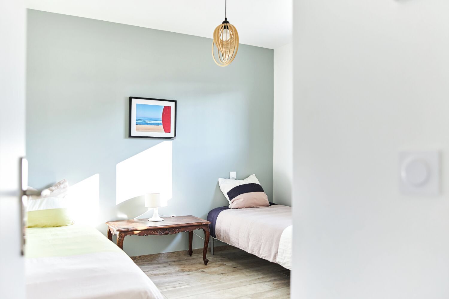 A bedroom with a bed, bedside table, lamp, and a hanging light fixture.