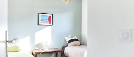 A bedroom with a bed, bedside table, lamp, and a hanging light fixture.