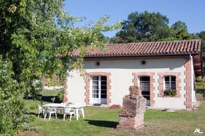 Traditional single-story building with a tiled roof and brick walls, featuring a front door and porch area.