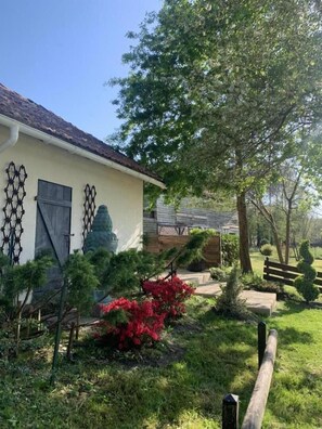 Una casa con jardín, cerca de madera y un árbol.