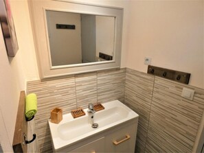 Ein Badezimmer mit Waschbecken, Spiegel und Holz-Handtuchhalter.