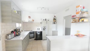 A modern kitchen with white cabinetry, a central island, and a built-in oven.