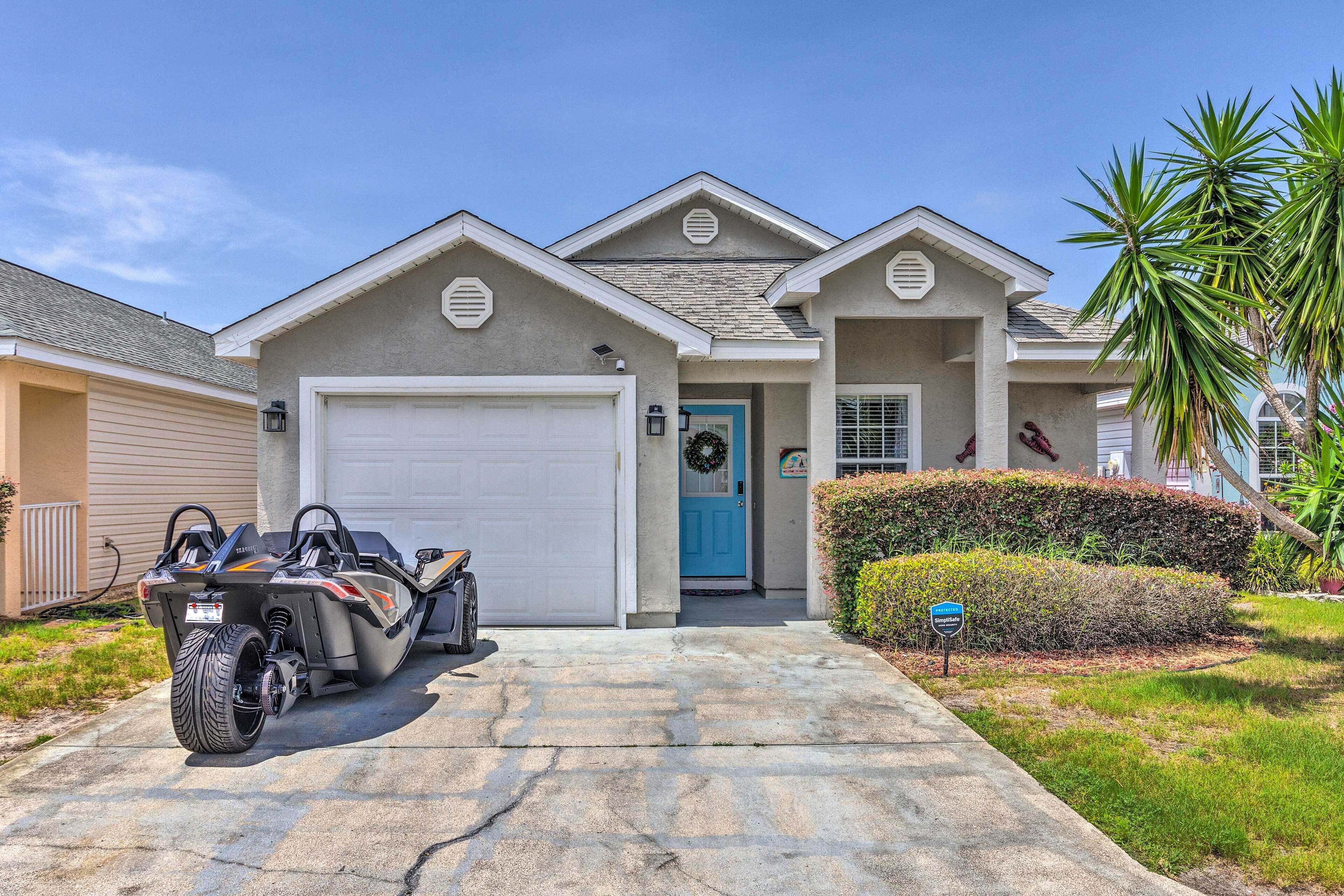 Une maison à deux étages avec un garage, une porte bleue et une moto garée devant.