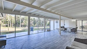 An open-plan living area with a wooden floor, large sliding glass doors leading to a backyard, and a dining area with a table and chairs. - Spacious Family Home w/ Backyard in Gainesville! (Gainesville)