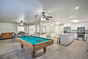 A modern living room with a pool table, a sofa, and a dining area. - Spacious Family Home w/ Backyard in Gainesville! (Gainesville)