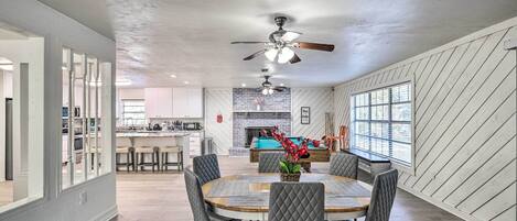 A spacious dining area with a round table, cushioned chairs, and a ceiling fan.