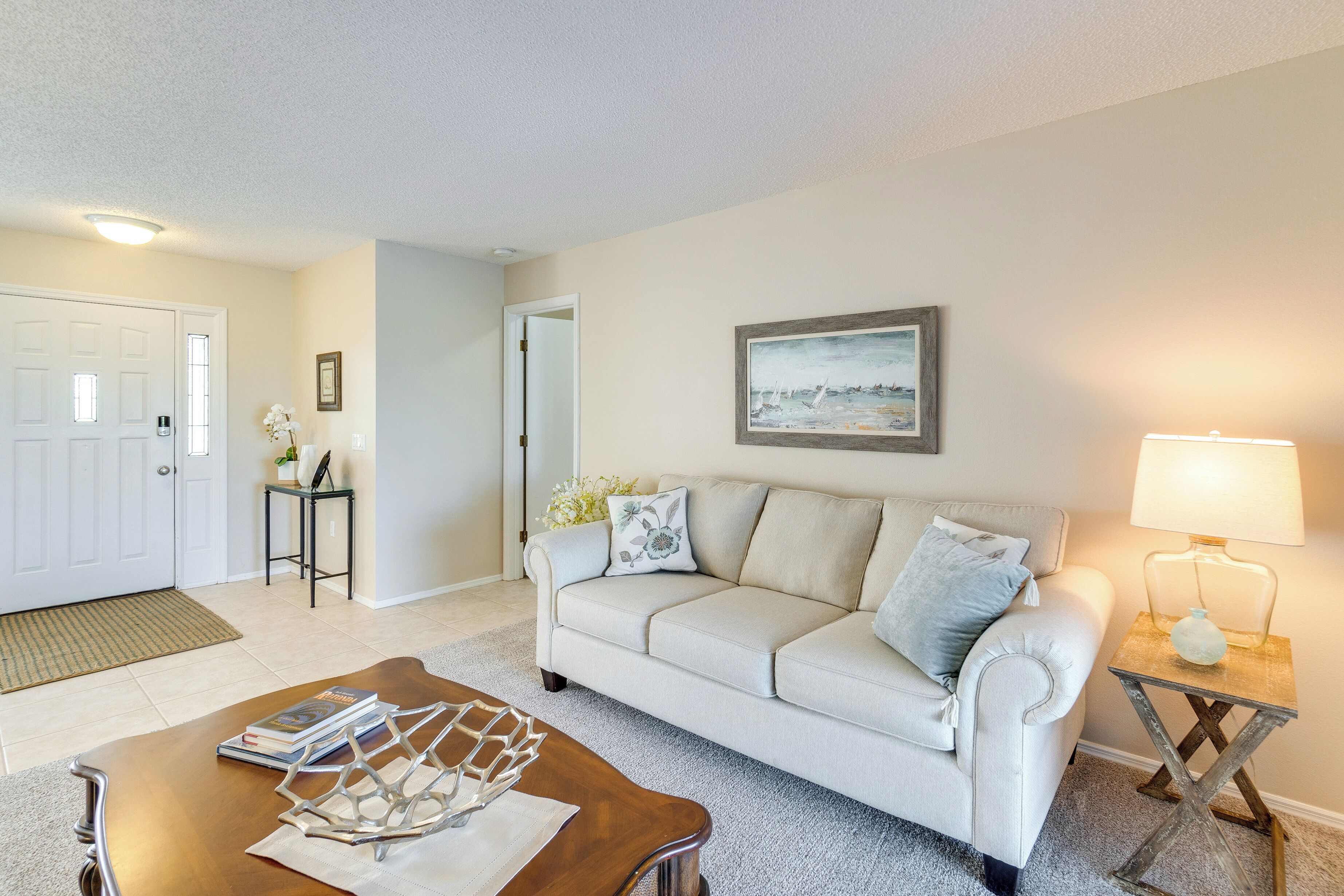 A living room with a white sofa, a coffee table, a lamp, and a framed picture on the wall.