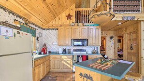 A wooden cabin kitchen with a central island, wooden cabinets, a microwave, and a stove. - Hurley Lakefront Hideaway w/ Fire Pit & Dock! (Hurley)
