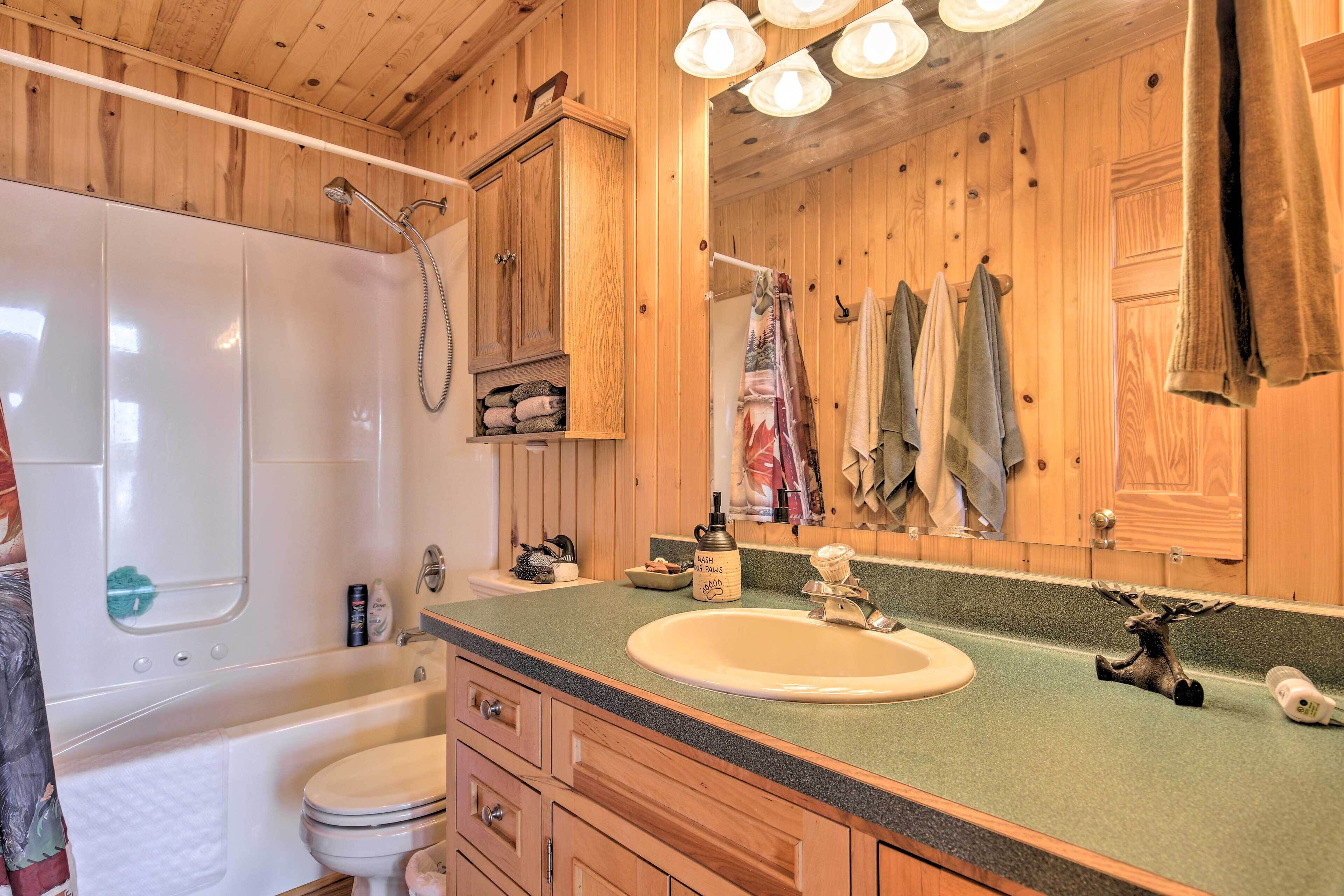 Une salle de bain en bois équipée d’une baignoire, de toilettes, d’un lavabo et d’un miroir.