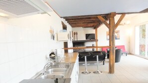 Een moderne keuken met een centraal eiland, een zithoek met een rode bank en een groot raam.