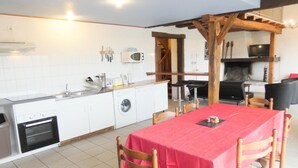 Een compacte keuken met een eethoek, inclusief een tafel met een rode tafelkleed en houten stoelen.