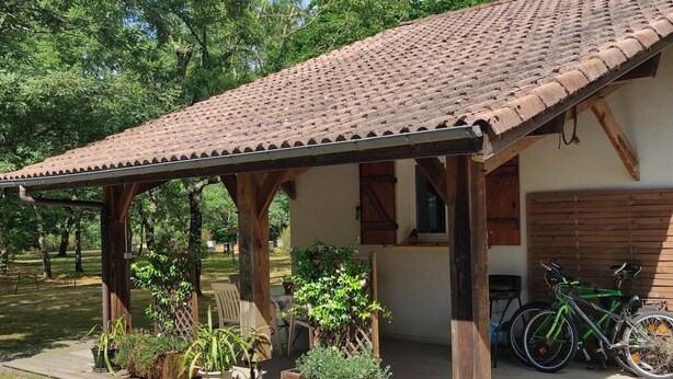 A covered patio with wooden beams, potted plants, and a bicycle.