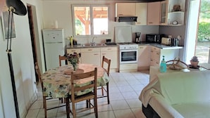 A compact kitchen with a dining area, a bed, and a window.