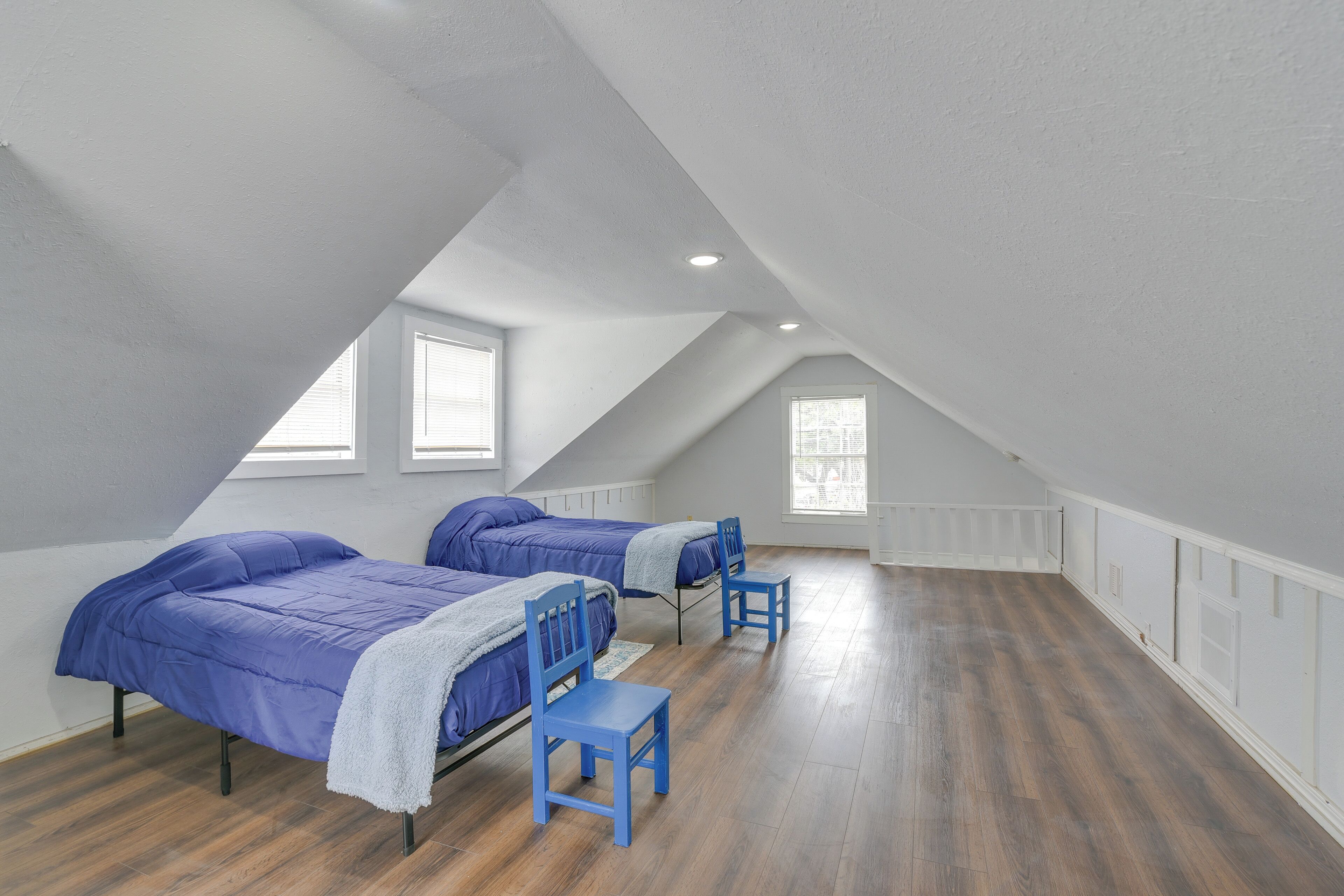 Un'ampia camera da letto mansardata con due letti, una sedia e una finestra.