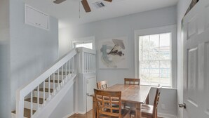 A dining area with a wooden table and chairs, a staircase, and a window with blinds. - 4 Blocks to Beach! Family-friendly Galveston Home (Galveston)