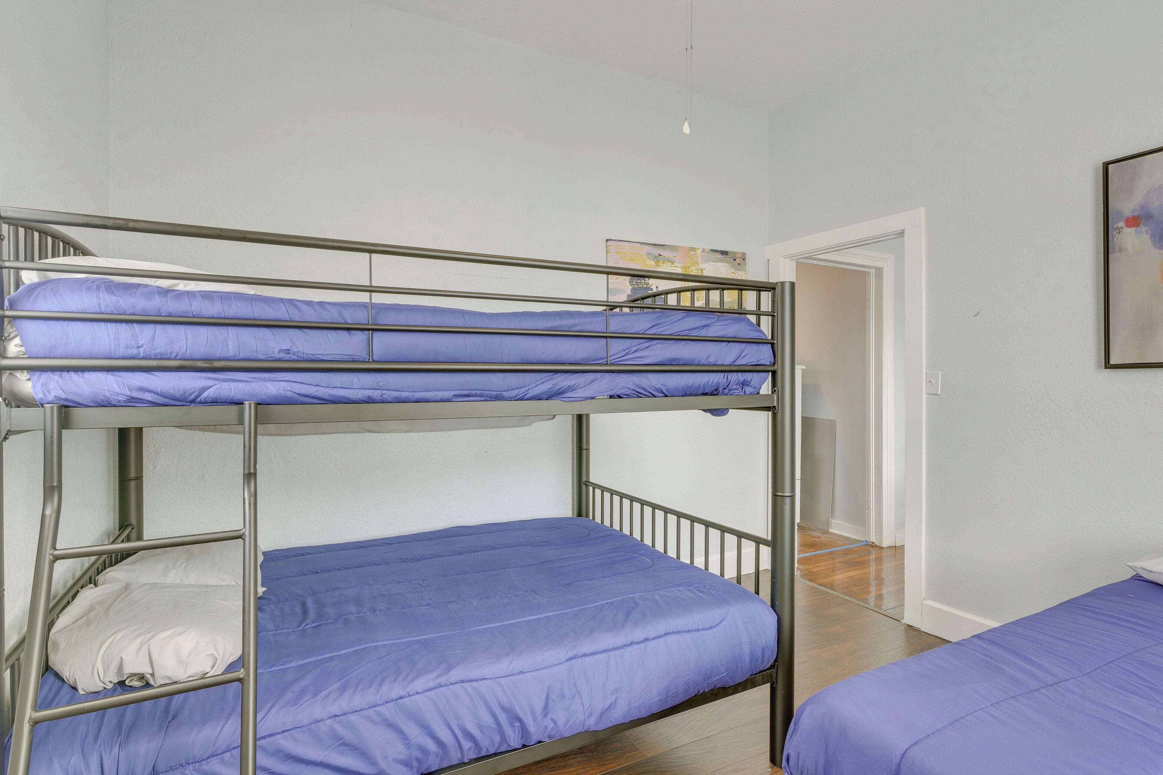 Une chambre avec un lit superposé, une porte blanche et un tableau accroché au mur.