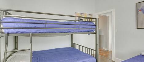 Une chambre avec un lit superposé, une porte blanche et un tableau accroché au mur.