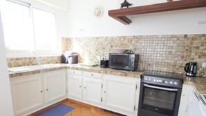 A kitchen with white cabinets, a tiled backsplash, a microwave, a stove, and a coffee maker. - La Tanière - St-martin-de-seignanx (ST-MARTIN-DE-SEIGNANX)