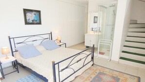 A bedroom with a bed, bedside tables, a nightstand, a bathroom with a sink and mirror, and a staircase. - La Tanière - St-martin-de-seignanx (ST-MARTIN-DE-SEIGNANX)