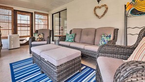 A cozy living area with wicker furniture, a blue striped rug, and a heart-shaped decoration on the wall. - Outdoor Retreat in Edgewater w/ Private Pool (Edgewater)