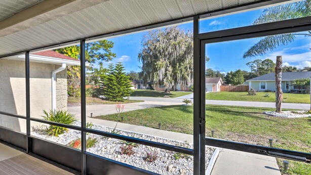 A room with large windows offering a view of a residential neighborhood, including houses and trees. - Outdoor Retreat in Edgewater w/ Private Pool (Edgewater)
