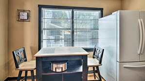 Eine Küche mit Fenster, Kühlschrank und Tisch mit Stühlen.