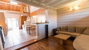 A spacious living area with a wooden floor, a sofa, a coffee table, and a staircase leading to an upper level.