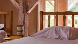 A wooden bed with a headboard in a rustic room with exposed beams and a window.