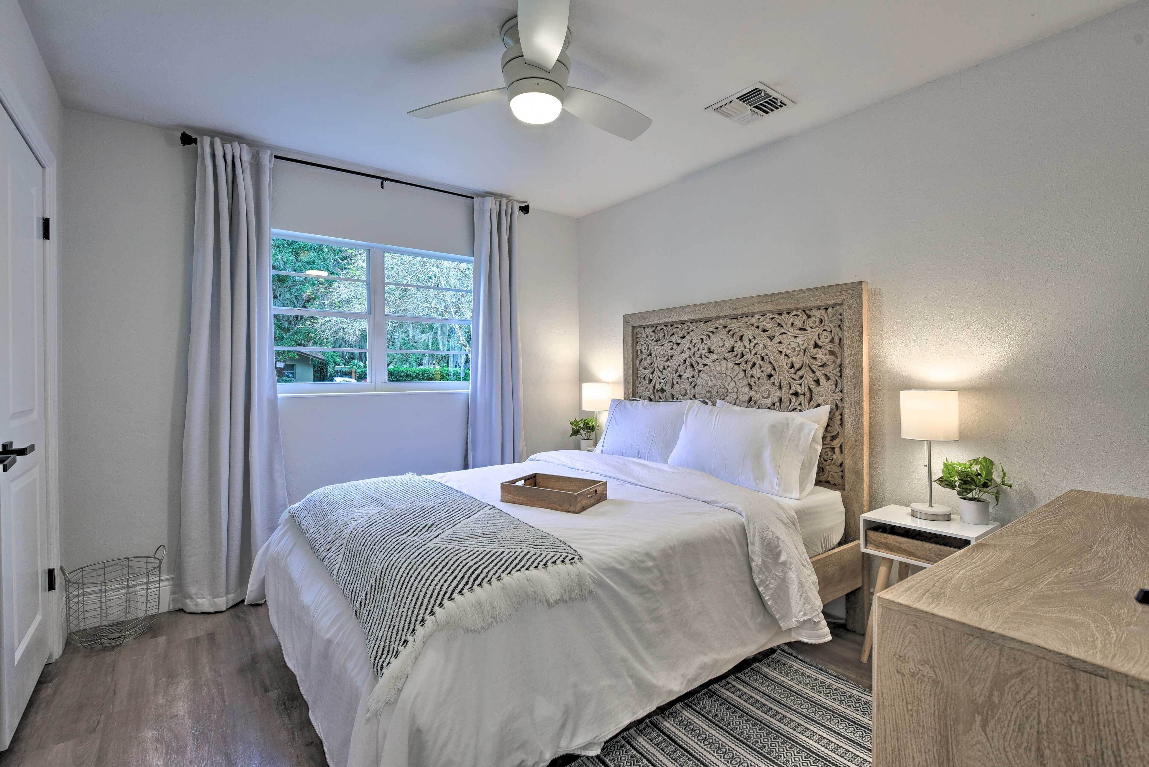 A neatly arranged bedroom with a bed, bedside tables, a ceiling fan, and a window with curtains.