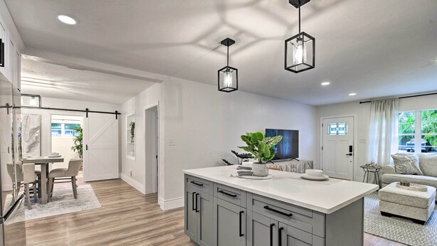 A modern kitchen with grey cabinets, a white countertop, and pendant lighting.