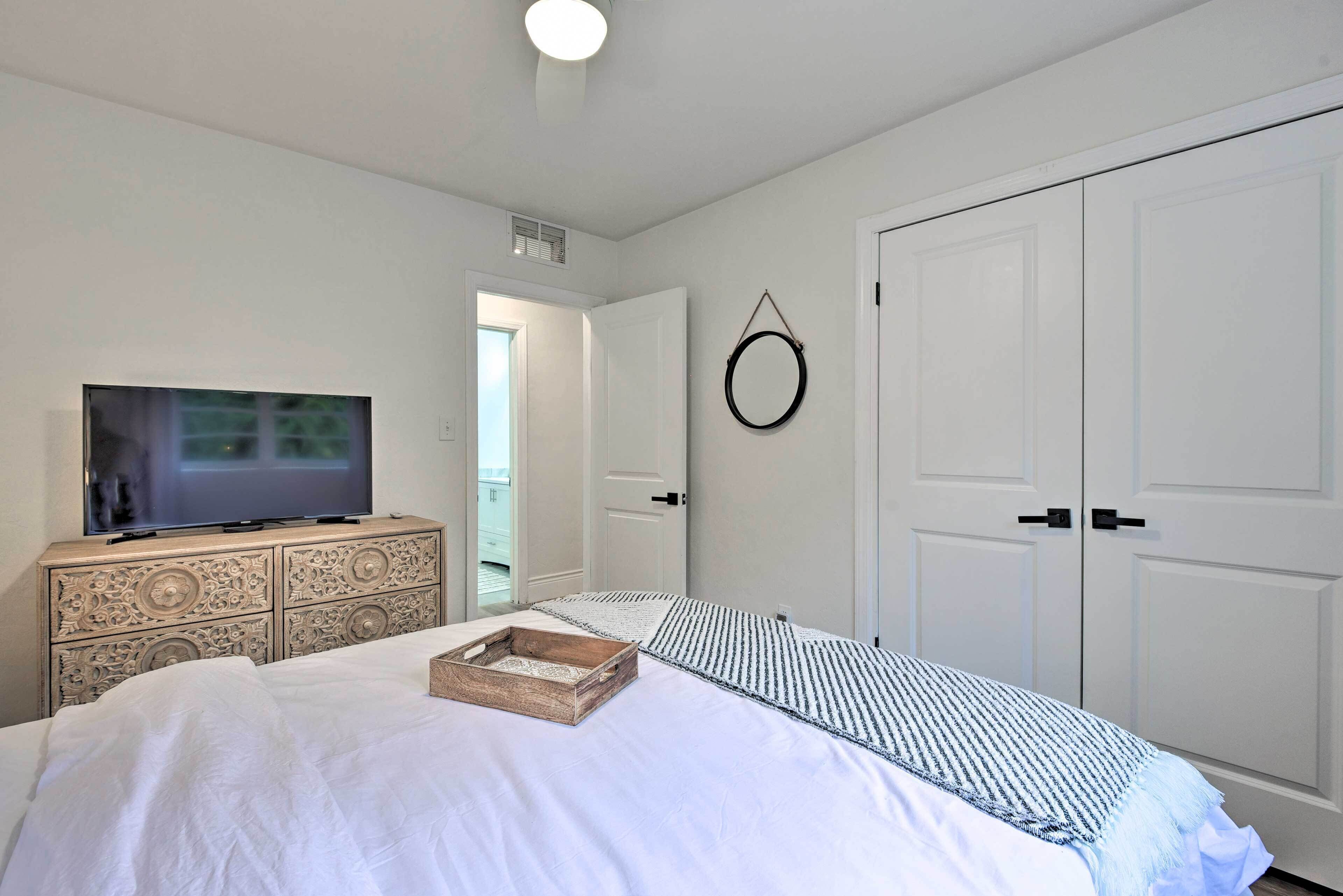A bedroom with a bed, a dresser, a television, a wardrobe, and a circular wall decoration.